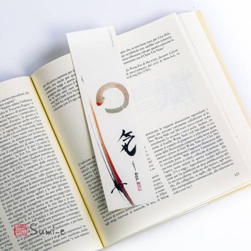 segnalibro di pittura sumi-e rappresentante la spada o katana del samurai stilizzata con enso e calligrafia su carta avorio con libro aperto