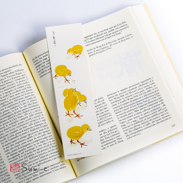 segnalibro di pittura sumi-e rappresentante dei pulcini gialli su carta avorio con libro aperto